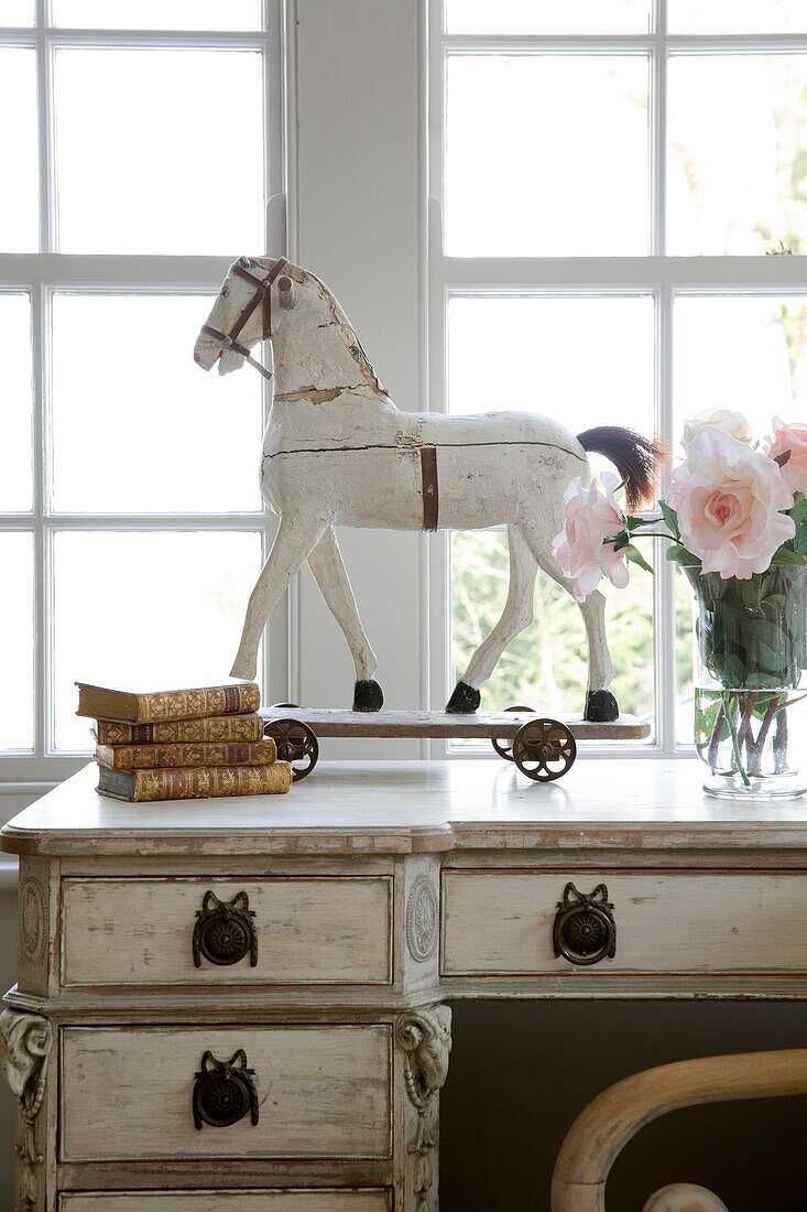 Toy horse and books on dressing table at bedroom window of historic Sussex country home England UK