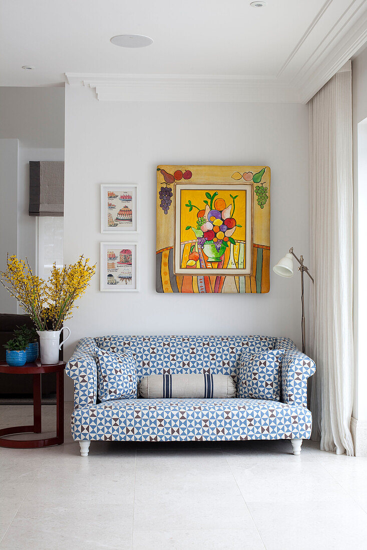 Zweisitzer-Sofa mit modernem Kunstwerk im Wohnzimmer eines modernen Landhauses in Surrey, England UK