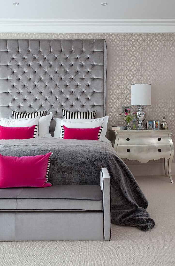 Rosa und graues Schlafzimmer mit übergroßem gepolstertem Kopfteil in einem modernen Landhaus in Surrey, England UK