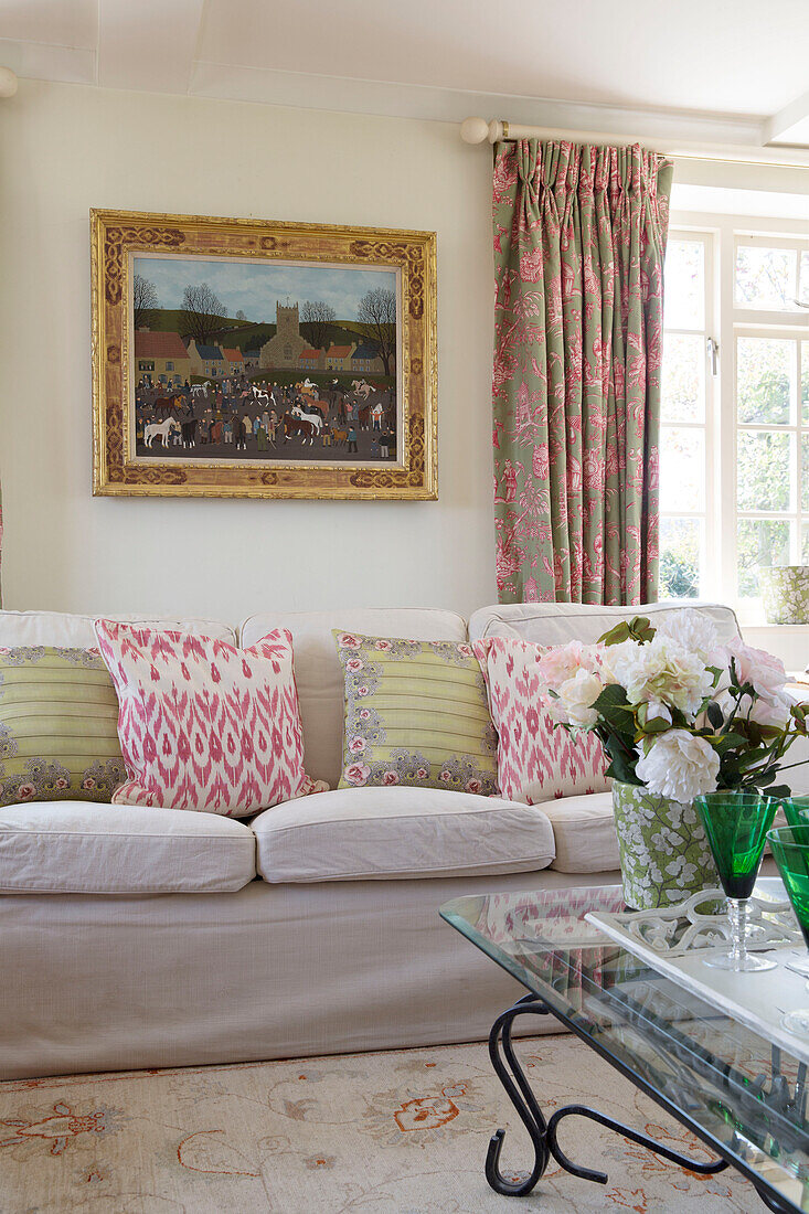 Gemusterte Kissen auf weißem Sofa mit Kunstwerken im Wohnzimmer eines Hauses in Sussex, England, UK