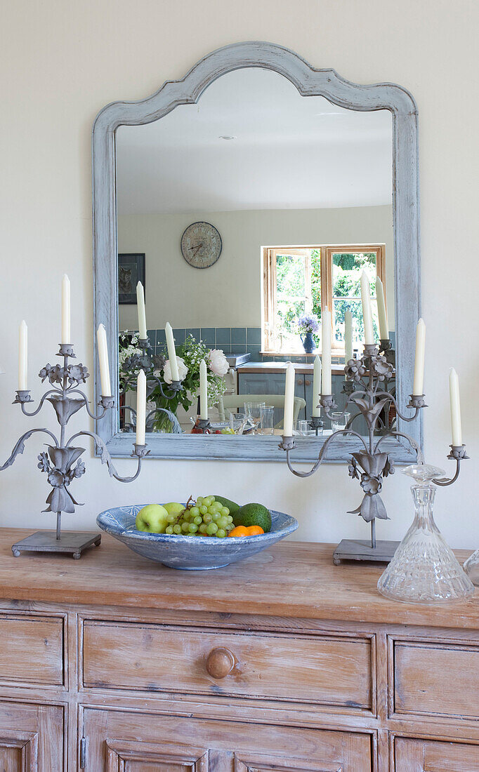 Light blue mirror frame above wooden sideboard in Sussex cottage, England, UK