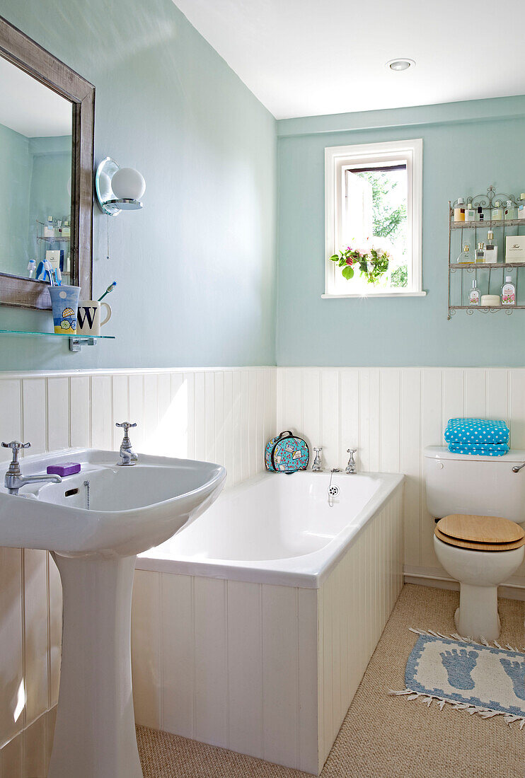 Pastellgrünes Badezimmer mit weißer Vertäfelung in einem Cottage in Sussex, England, UK