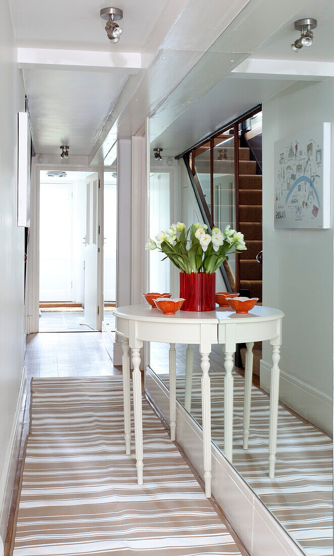 Demi-lune table in mirrored hallway of London townhouse, England, UK