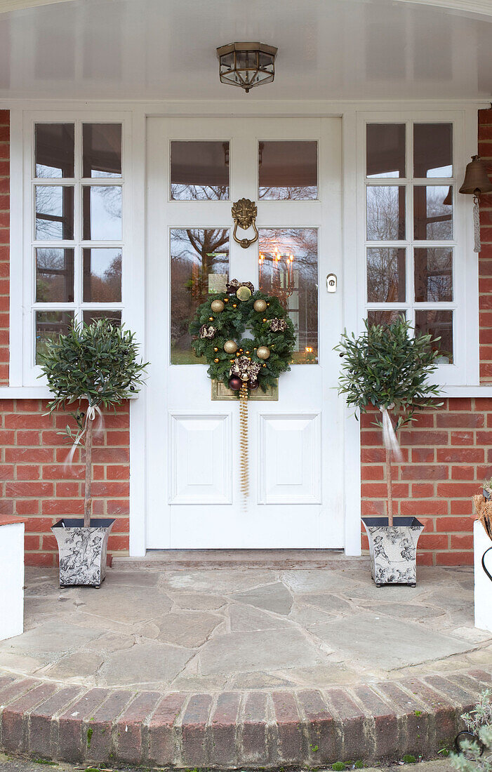 Blumenkranz und Topfpflanzen an der weißen Eingangstür eines Bauernhauses in Sussex, England, UK