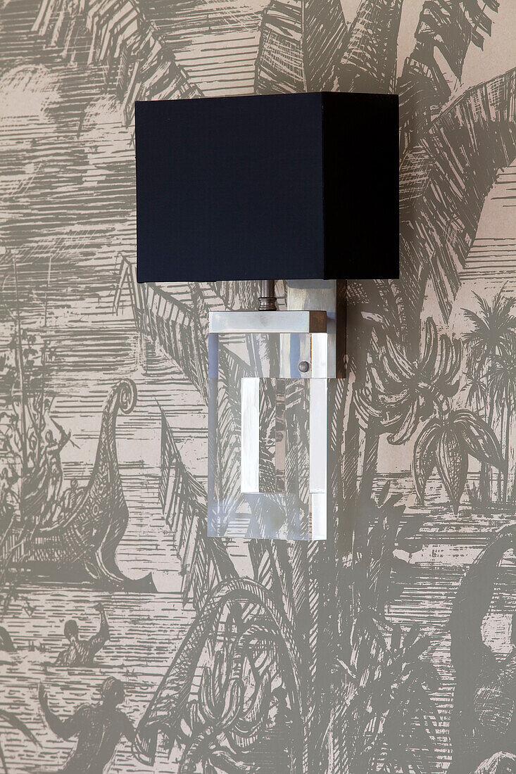 Contemporary black lamp on patterned wallpaper in Sussex country house, England, UK