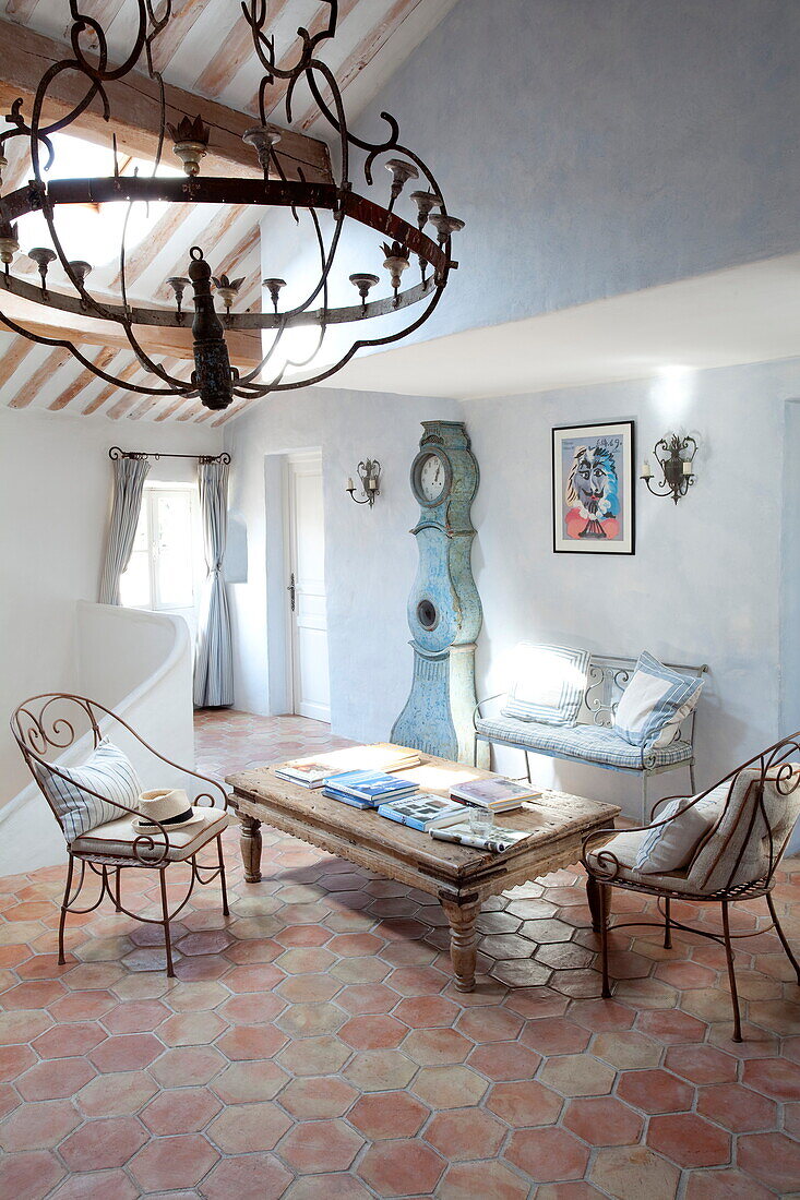 Metal chairs and coffee table with grandfather clock in attic room of Mougins apartment, Alpes-Maritime, South of France