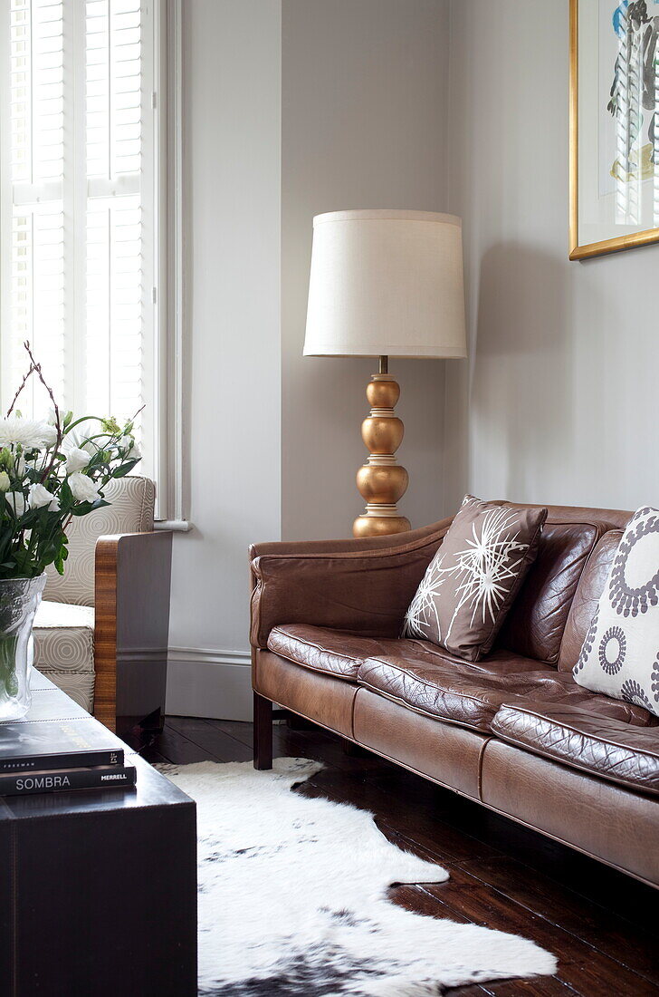 Standard lamp and animal skin rug with brown leather sofa in London townhouse, England, UK