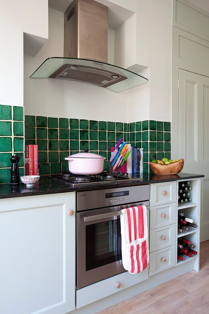 Auflaufform auf einem Gaskochfeld in einer Küche mit grüner Kachelrückwand in einem Londoner Haus, England, UK