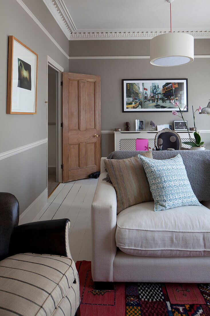 Wohnzimmer mit hellgrauen Wänden, weiß gestrichenen Dielen und Decke, Sofa und Tür aus gestrichener Kiefer