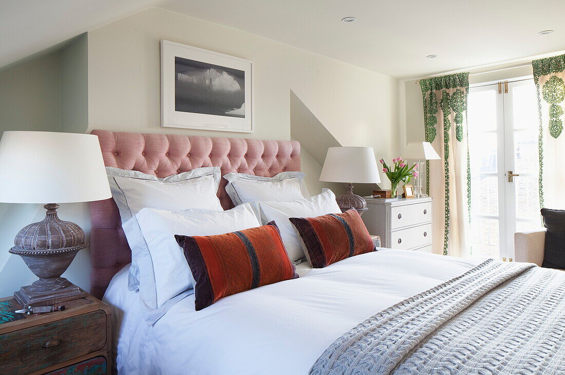Buttoned headboard with matching lamps and cushions in London home, England, UK