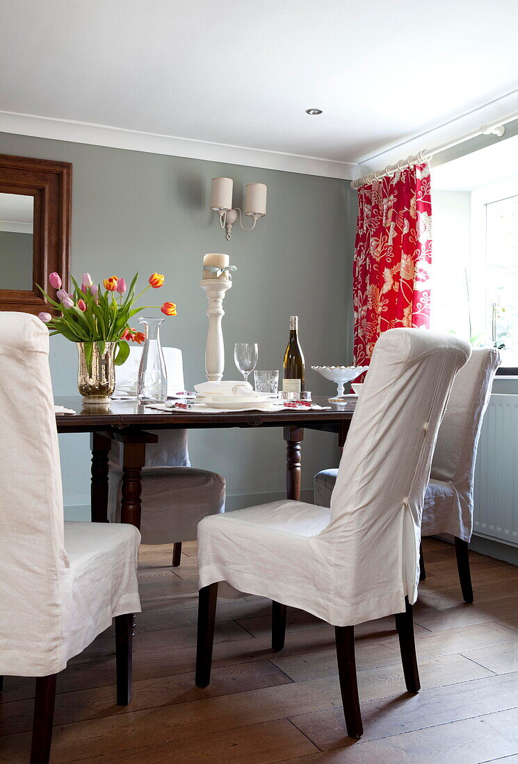 Überzüge auf Esszimmerstühlen am Tisch mit geschnittenen Tulpen in einem Bauernhaus in Staffordshire England UK