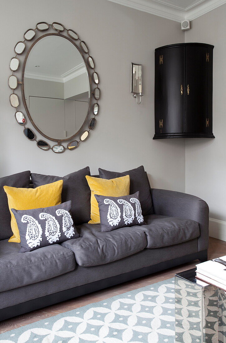 Large vintage mirror and corner cabinet with grey sofa in London townhouse England UK