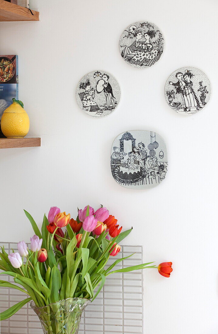 Dekorative Wandteller mit geschnittenen Tulpen in der Küche eines Hauses in Kent, England UK