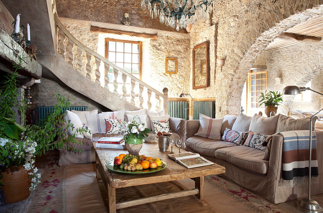 Couchtisch aus Holz mit Sofas in einem offenen Wohnzimmer aus Naturstein in einer französischen Ferienvilla