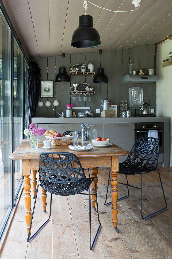 Schwarze Stühle am hölzernen Küchentisch in einem modernisierten bretonischen Landhaus in Westfrankreich