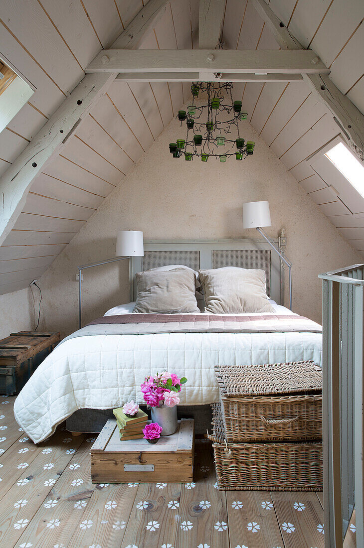 Körbe am Fußende des Bettes in einem Schlafzimmer im Dachgeschoss eines bretonischen Landhauses in Westfrankreich