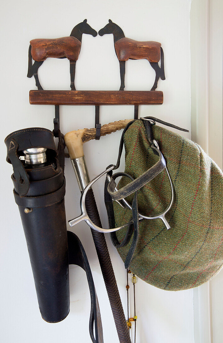 Flachmütze und Fernrohr mit Reitsporen an einem Haken im Haus in den Sussex Downs, England, UK