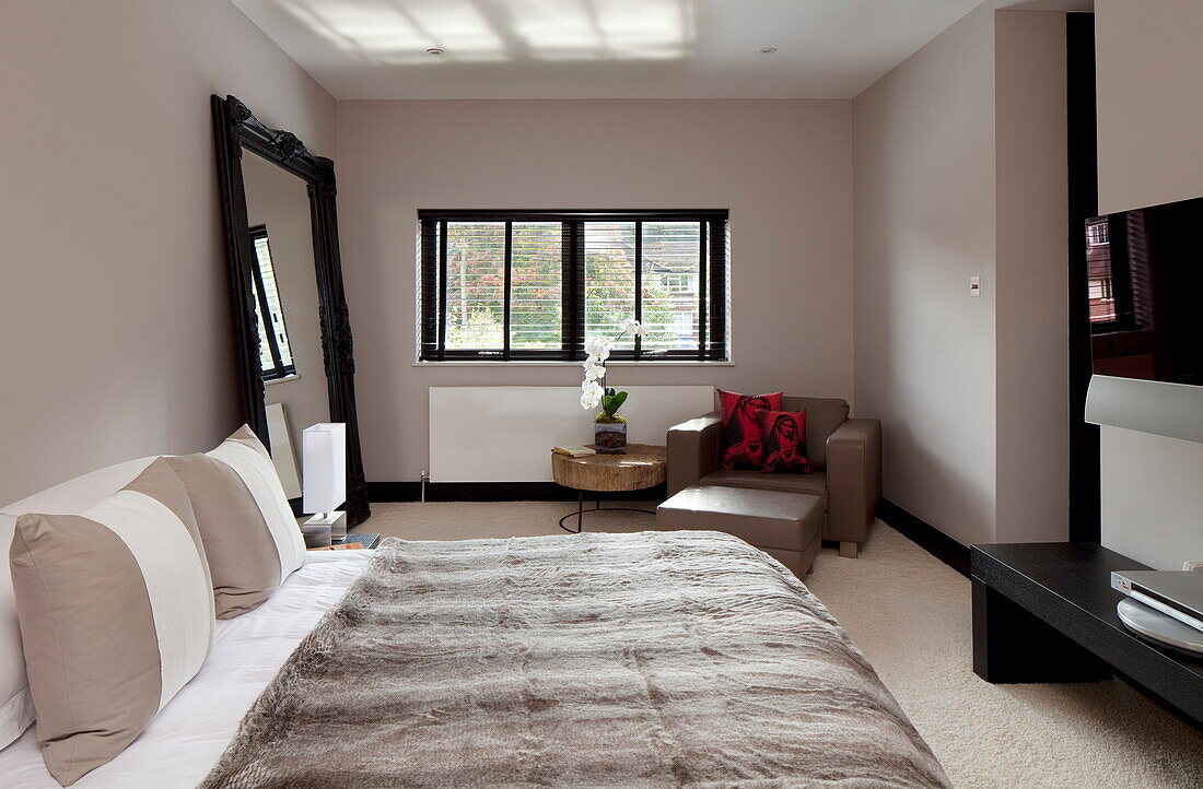 Pelzdecke auf dem Bett mit großem Spiegel in einem modernen Haus, Kingston upon Thames, England, UK