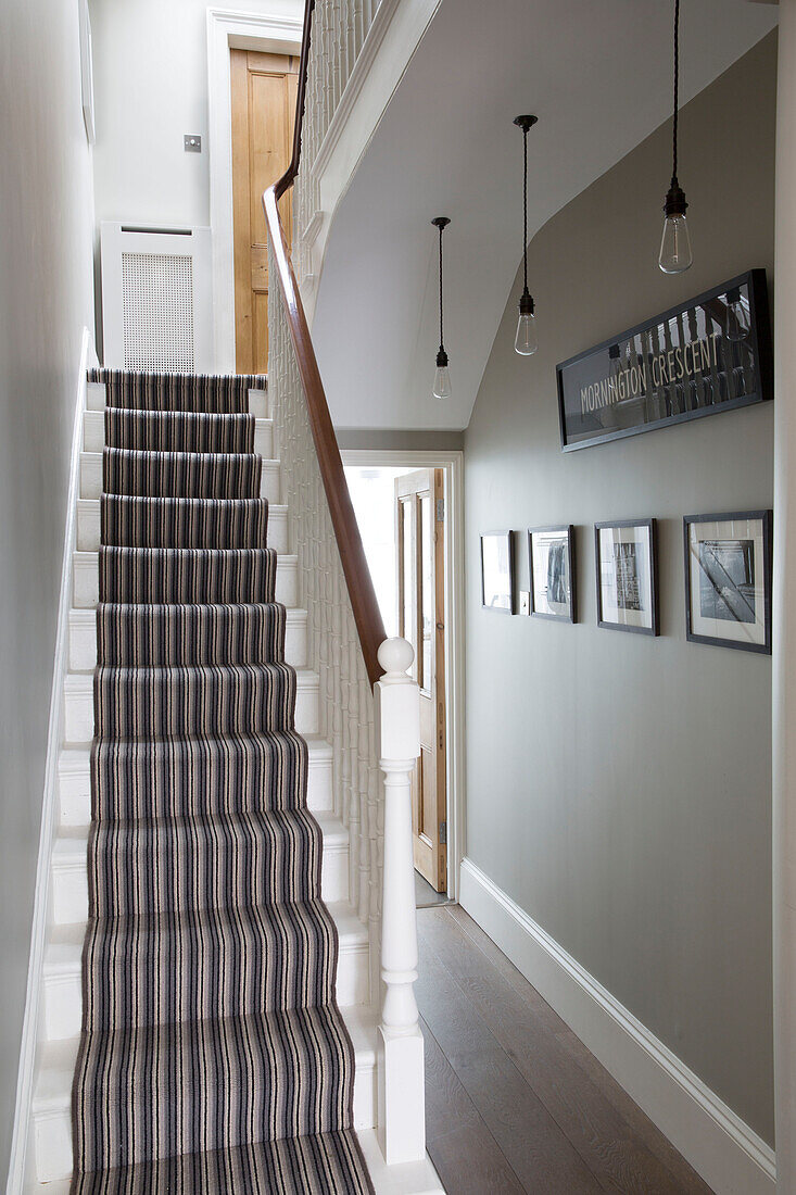 Gestreifter Teppich und Kunstwerke im Treppenhaus eines modernen Hauses in Brighton, East Sussex, England, UK