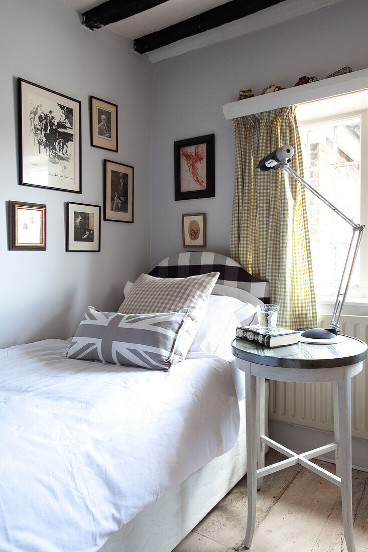 Einzelbett mit Union-Jack-Kissen und Schwarz-Weiß-Fotos in einem Haus in West Sussex, England, Vereinigtes Königreich