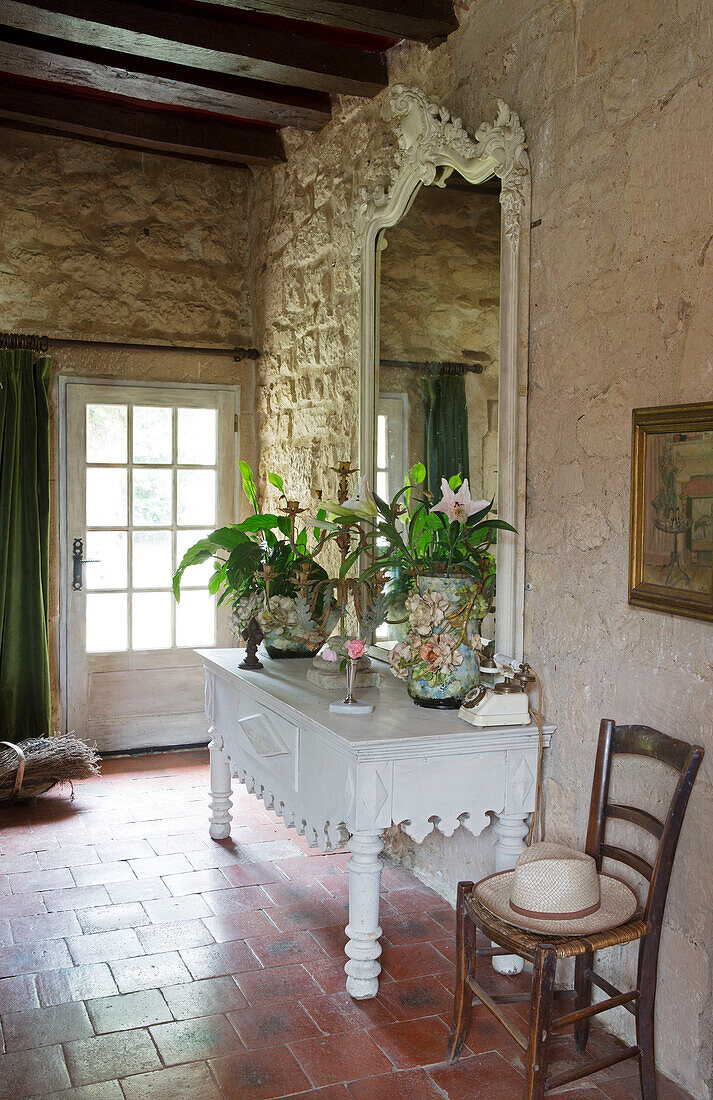 Large mirror on painted side table in exposed stone hallway of French farmhouse in the Loire, France, Europe
