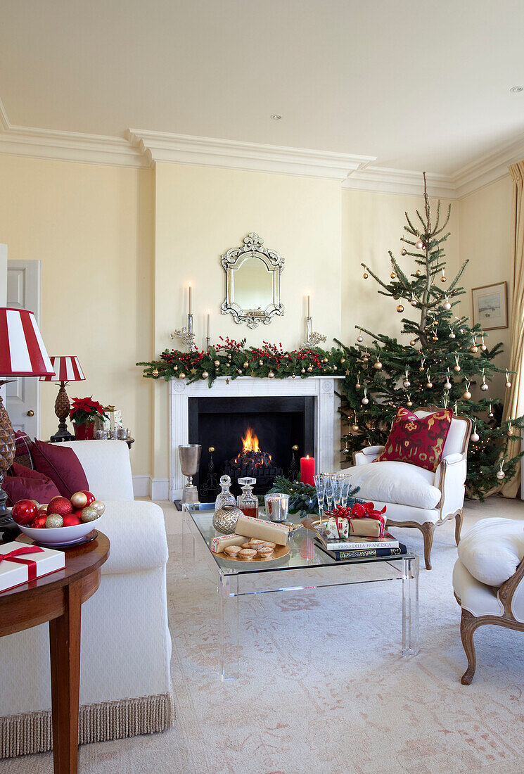 Weihnachtsbaum vor dem Kamin mit gläsernem Couchtisch in einem Haus in West Sussex, England, Vereinigtes Königreich