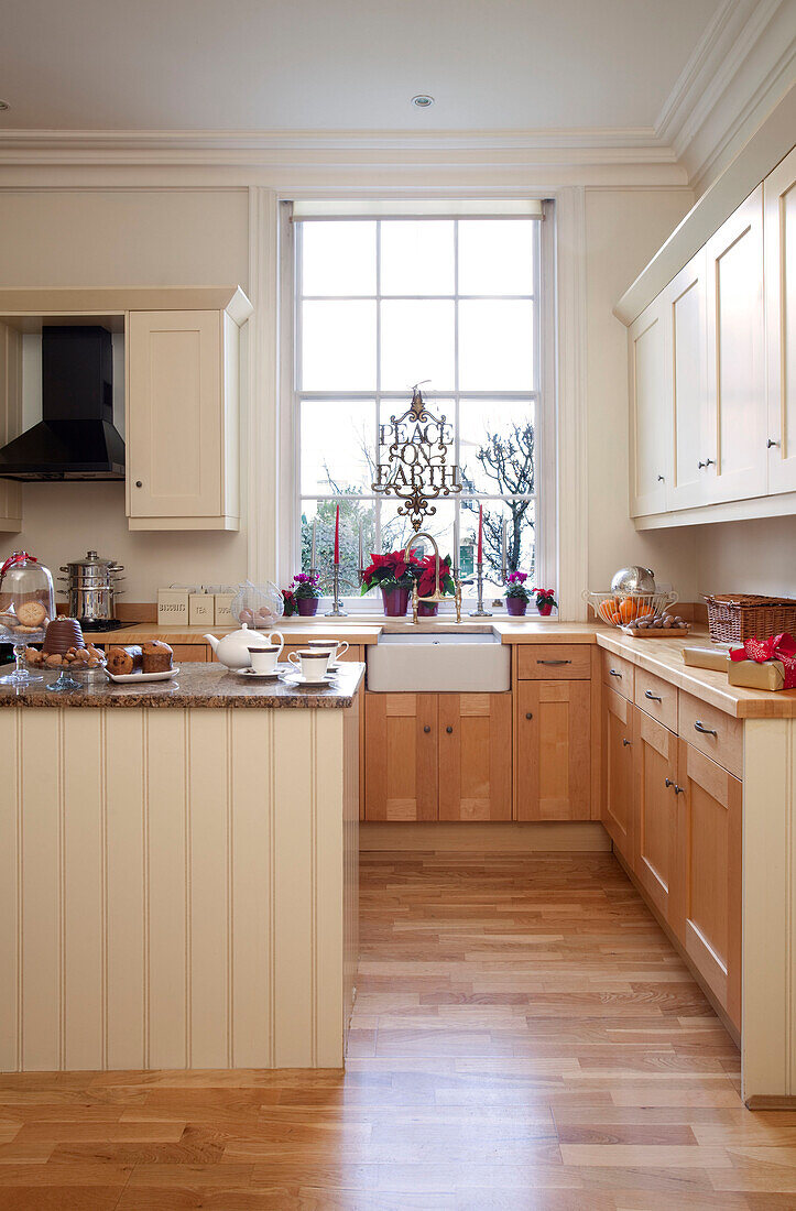 Cremefarbene Küche mit Nut und Feder und Holzlaminatboden in einem Haus in West Sussex, England, UK