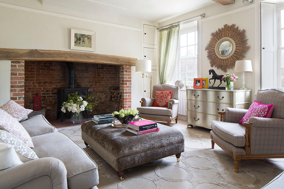 Pair of armchairs and ottoman with exposed brick fireplace in living room of London home England UK