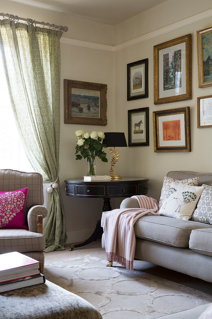 Beistelltisch aus Holz und Sofa mit gerahmten Kunstwerken im Wohnzimmer eines Hauses in London England UK