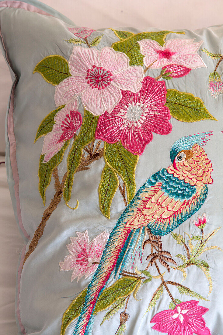 Embroidered floral design with parrot on cushion in London home England UK
