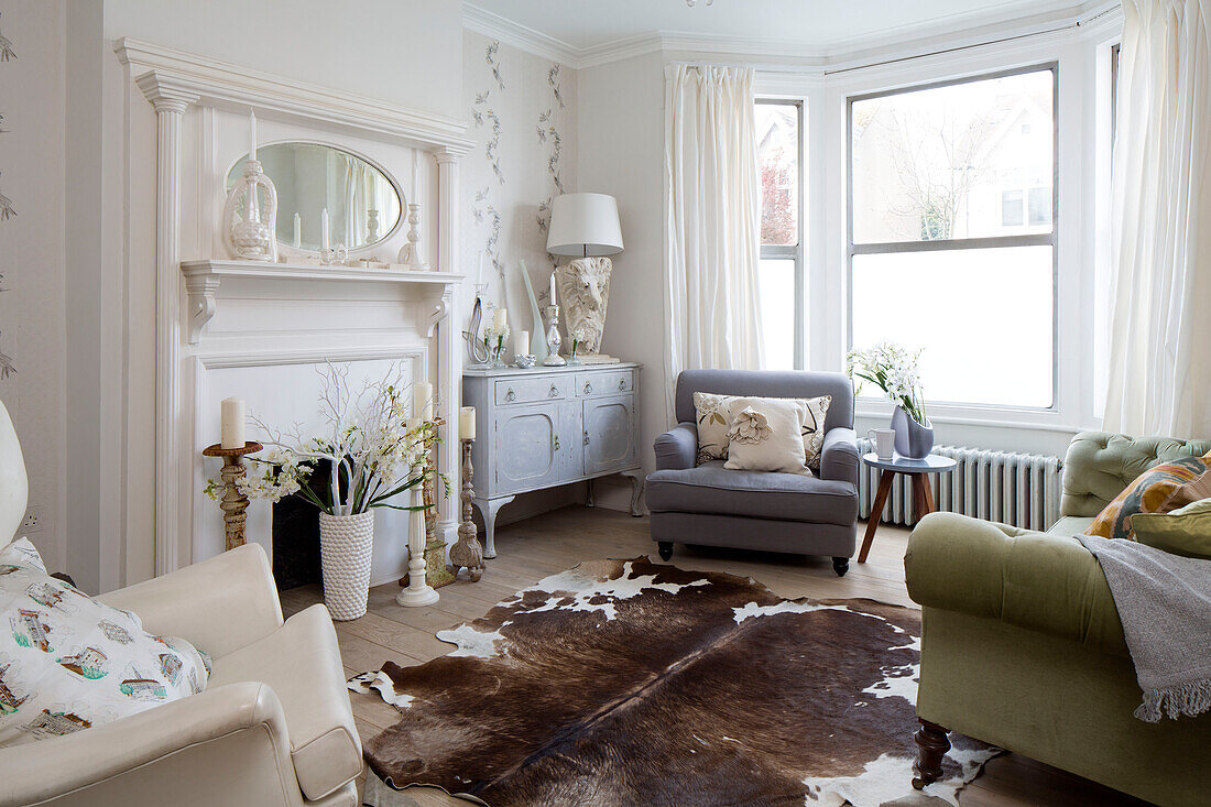 Geknöpftes Sofa mit grauem Sessel und Tierfellteppich im Wohnzimmer eines Londoner Stadthauses, England, UK