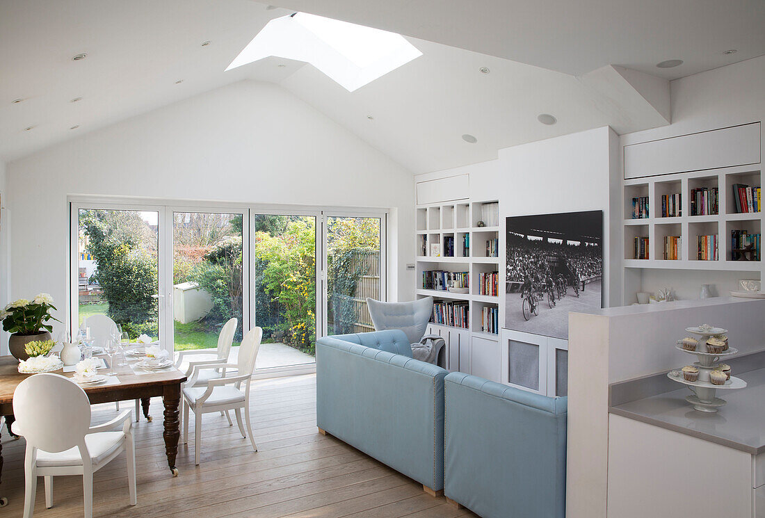 Offenes Esszimmer mit blauen Ledersofas und Bücherregal in einem Stadthaus in London, England, UK