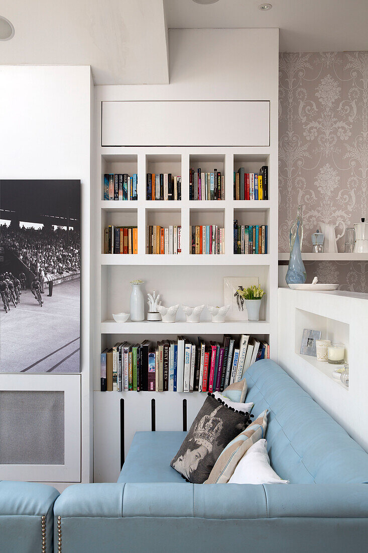 Light blue leather sofa with bookcase in living room of London townhouse, England, UK