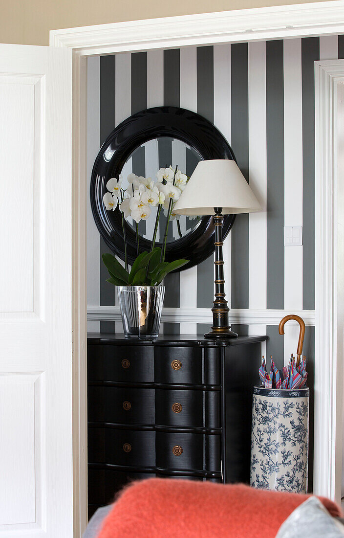 Mirror above sideboard in black and white striped hallway of London home, England, UK