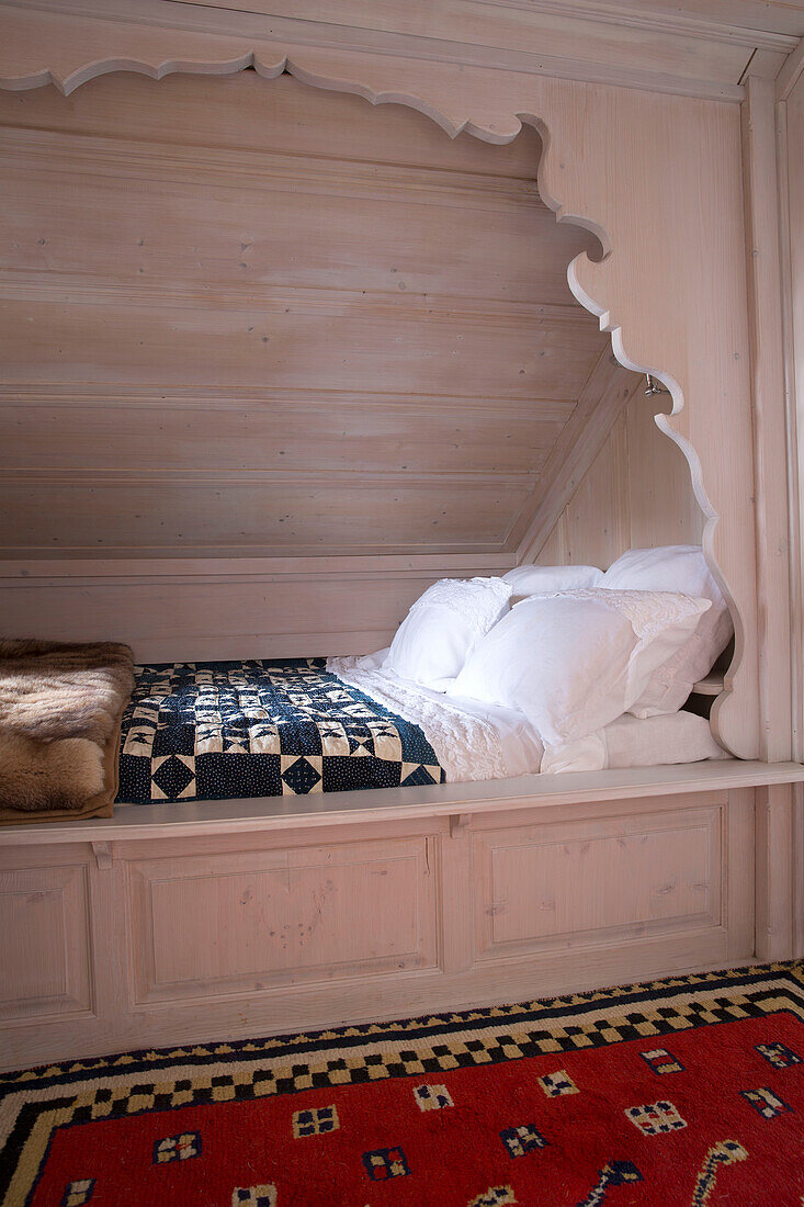 Vertieftes Bett mit geschnitzter Holznische in einem Bergchalet in Chateau-d'Oex, Waadt, Schweiz