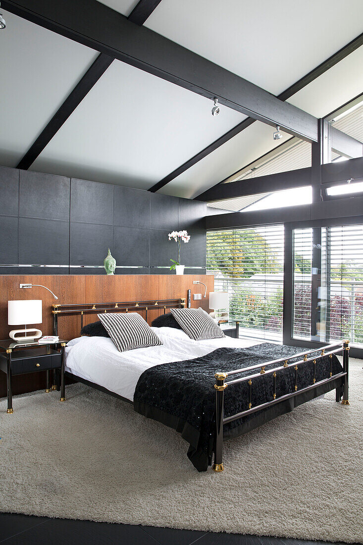 Black double bed with wooden panel in spacious contemporary SW London home England UK