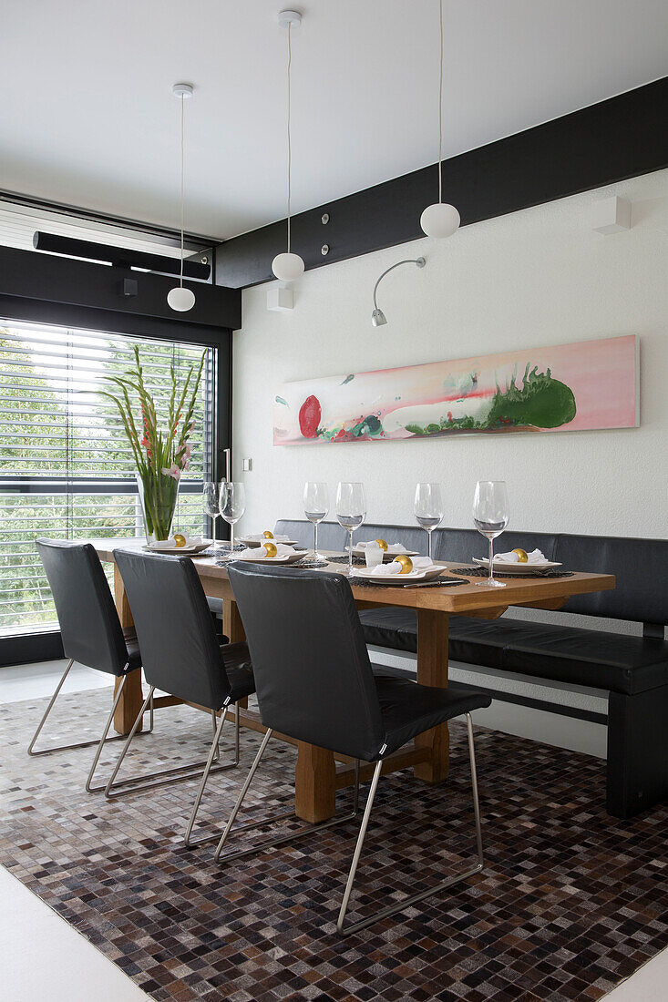 Schwarze Lederstühle und Sitzbank mit braunem Mosaikteppich in einem modernen Haus im Südwesten Londons UK
