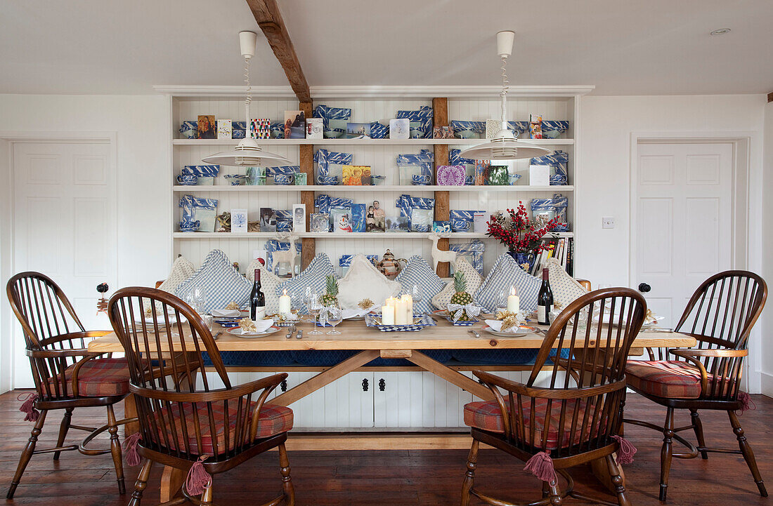 Tartan seat cushions on wooden chairs at dining table below open shelves in Chilterns home, England, UK