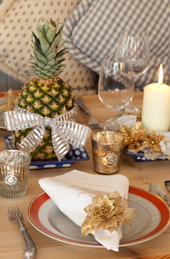 Lit tealights at place setting with pineapple on Chilterns dining table, England, UK