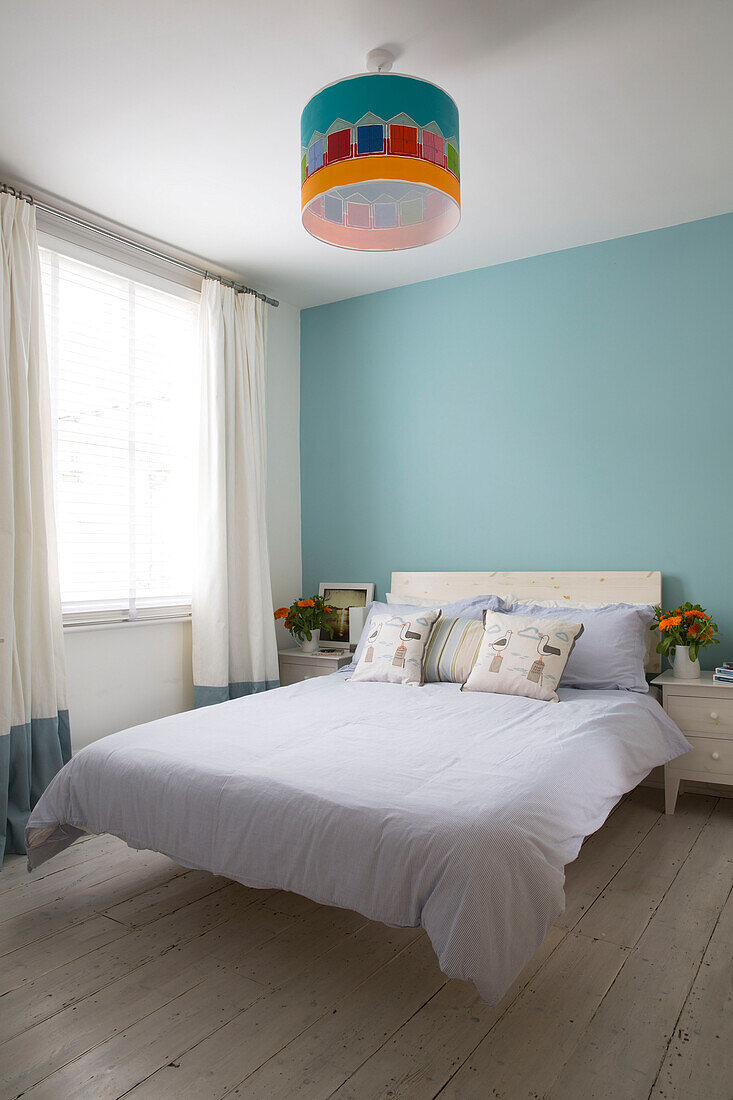 Weiße Bettdecke auf einem schwebenden Doppelbett in einem türkisfarbenen Zimmer eines modernen Hauses in Brighton, East Sussex, England, UK