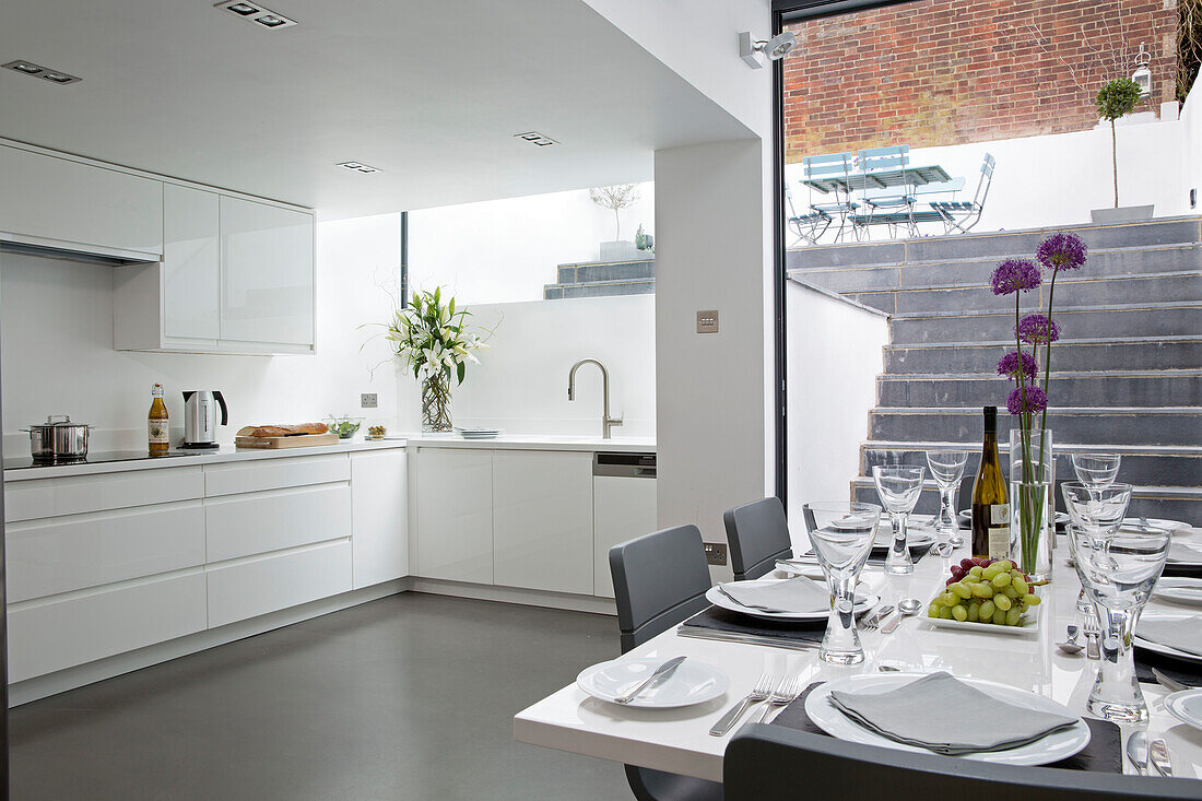 Offene Kellerküche mit gedecktem Tisch in einem modernen Haus in Brighton, East Sussex, England, UK