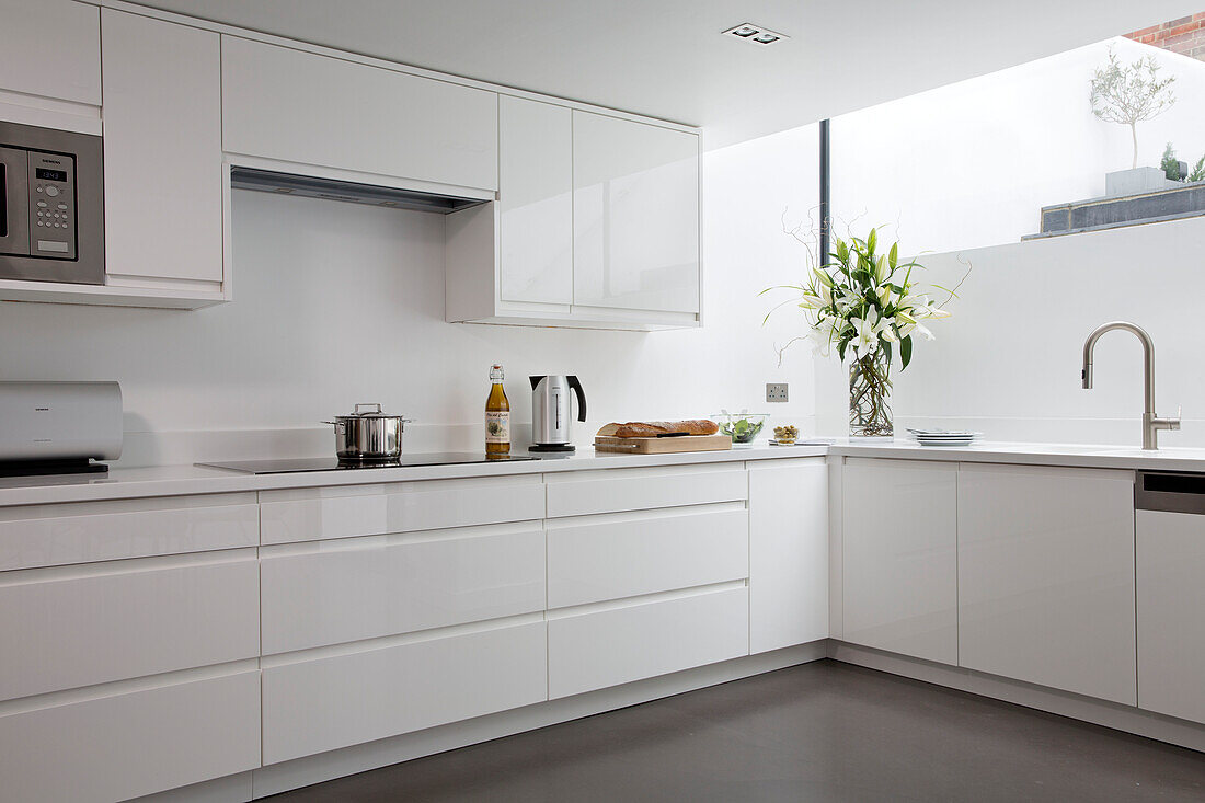 Cut lilies in white fitted kitchen of contemporary Brighton home East Sussex England UK