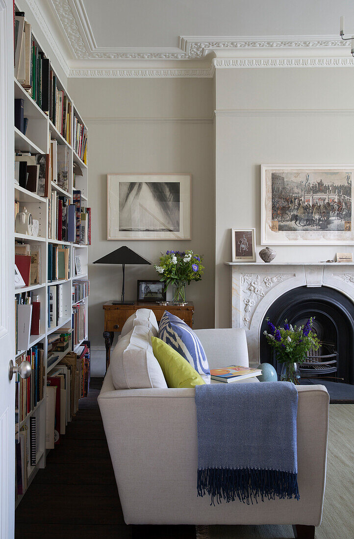 Weißes Sofa und Bücherregal mit Kamin im Wohnzimmer in Oxfordshire, England UK