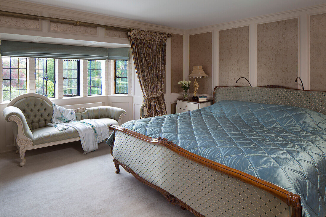Gestepptes Kingsize-Bett mit Chaiselongue vor einem bleiverglasten Fenster in einem Londoner Haus, UK