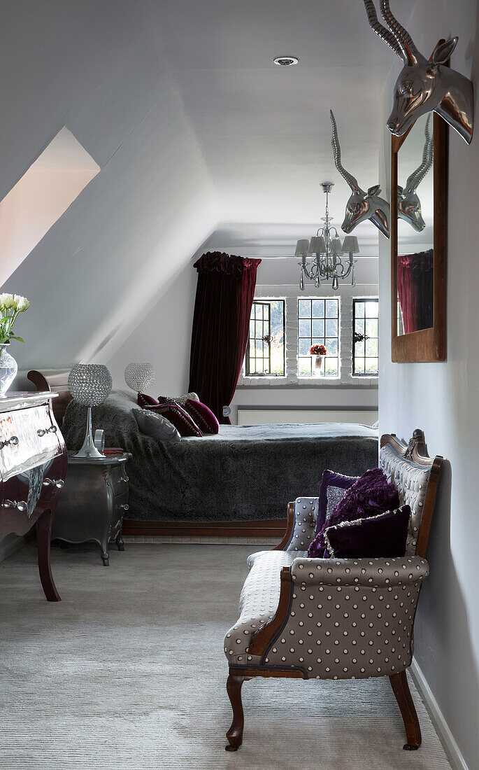 Metallische Antilopenköpfe über einem Sessel in einem klassischen Schlafzimmer im Dachgeschoss eines Londoner Hauses, UK