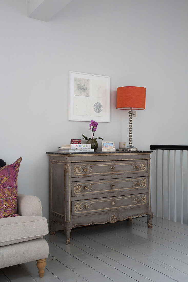 Orange lamp on vintage chest of drawers in London townhouse England UK