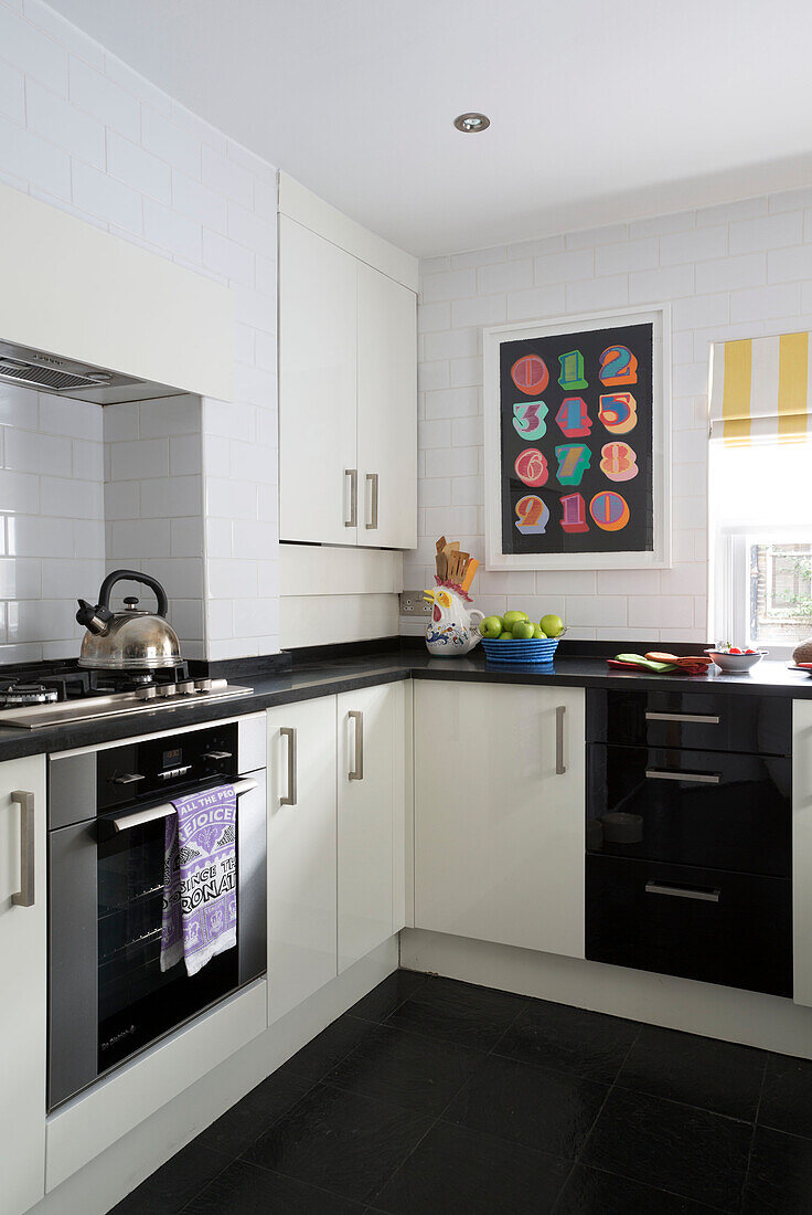 Modernes Kunstwerk in der schwarz-weißen Einbauküche eines Londoner Stadthauses England UK