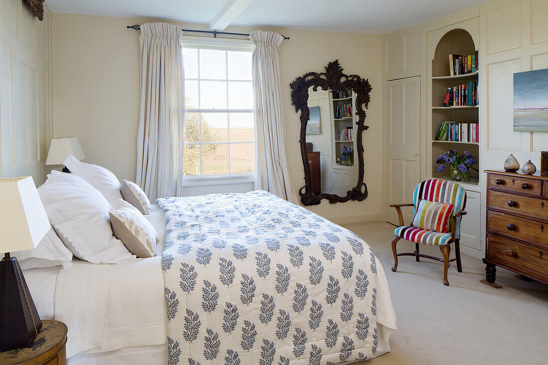 Bettdecke mit Blattmotiv im Schlafzimmer mit dekorativem Spiegel und gestreiftem Sessel in einem Cottage in Camber, East Sussex, England, Vereinigtes Königreich
