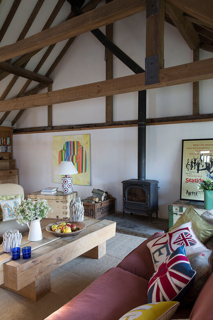 Cushions on pink sofa with low coffee table and woodburning stove in Camber cottage East Sussex England UK