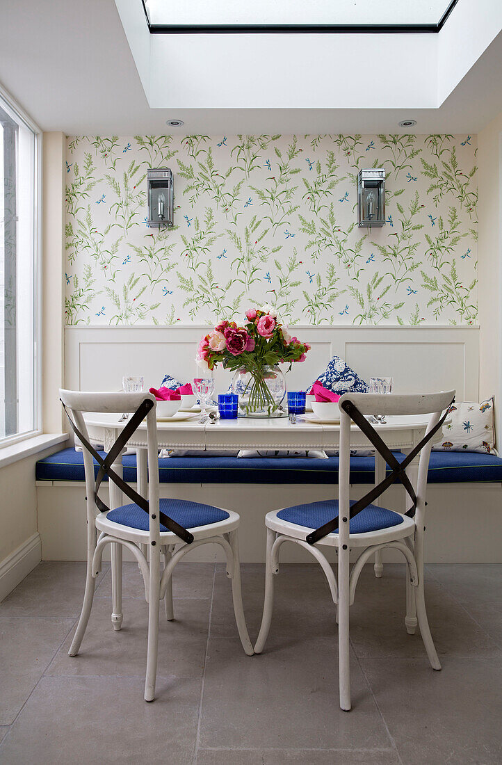 Schnittblumen auf einem Küchentisch mit blauen Stühlen in einem Stadthaus in London, England, Vereinigtes Königreich